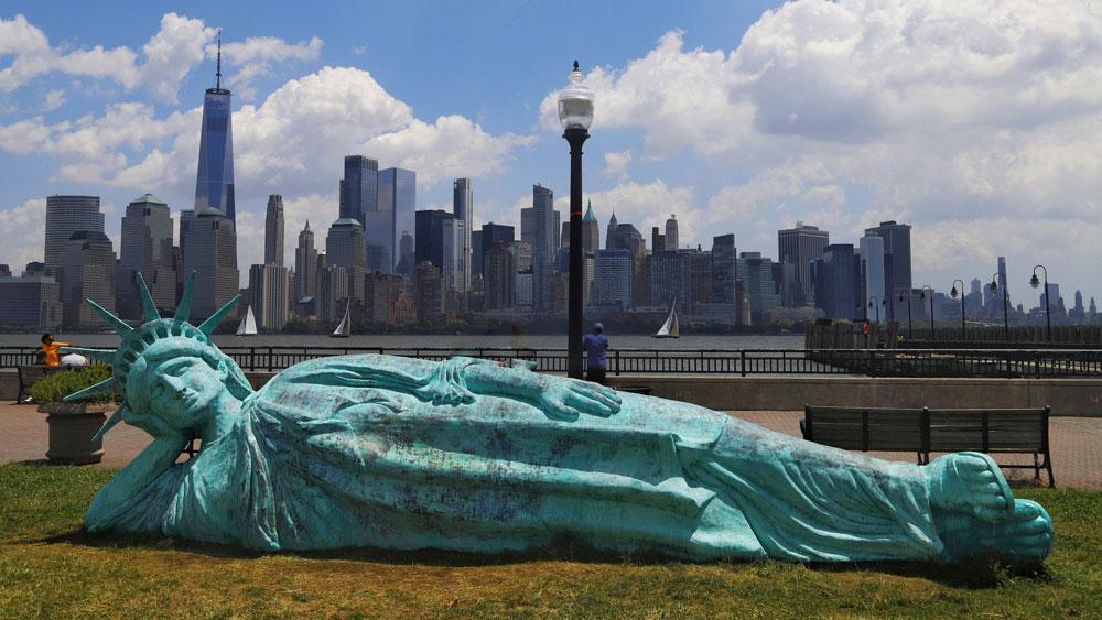 Bild: "Reclining Liberty", eine liegende Freiheitsstatue in einem Park vor der Skyline der Südspitze Manhattens