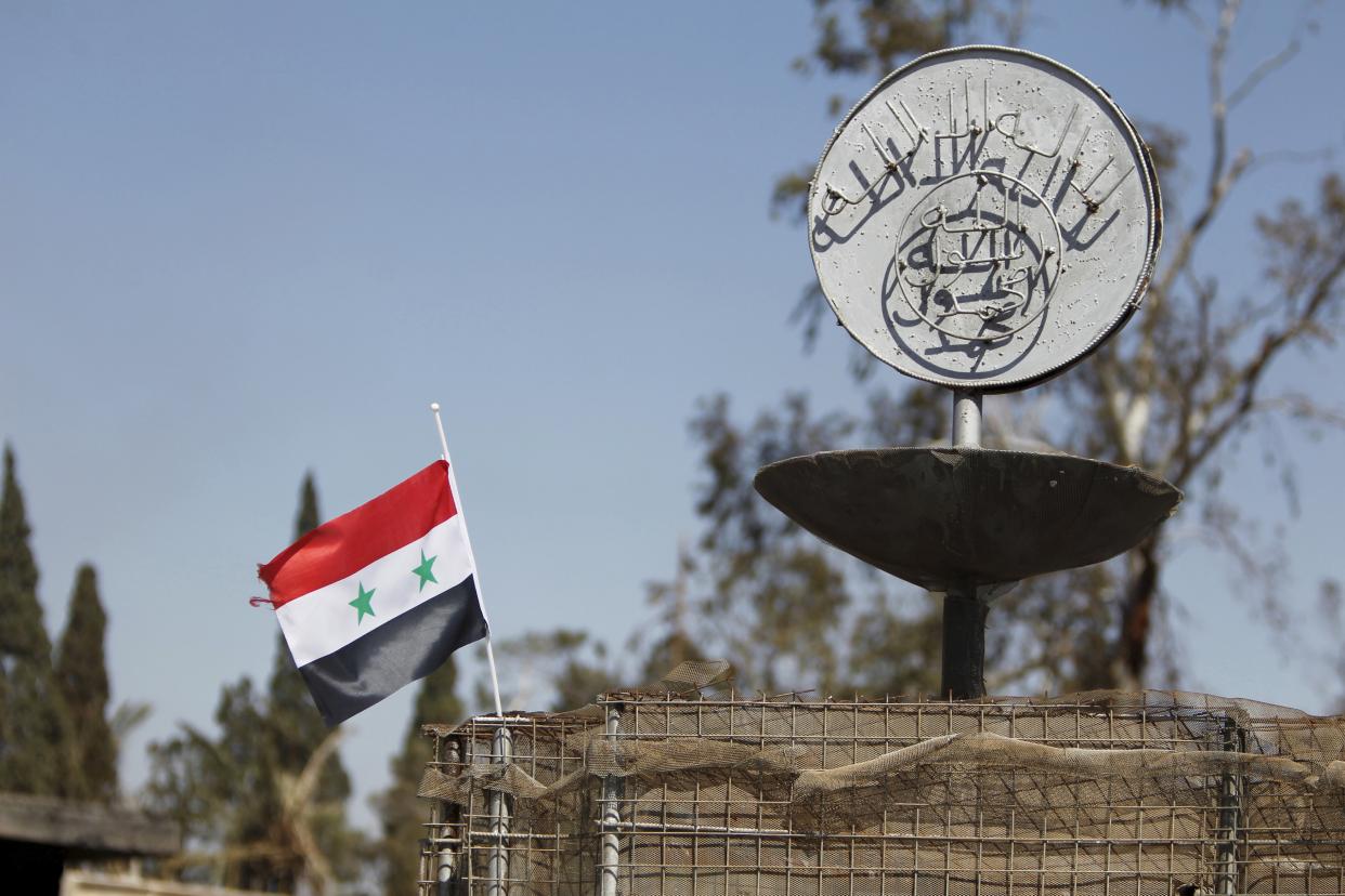 Bild: Insignien des IS vor einer syrischen Flagge