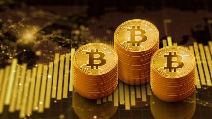 Bild: Illustration von drei Stapeln goldener Bitcoin-Münzen vor einem stilisierten Finanzdiagramm.