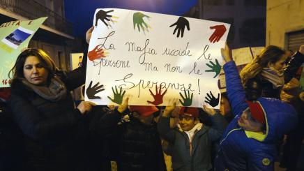Bild: Erwachsene und Kinder bei einer Demonstration halten ein Plakat mit bunten Handabdrücken und der italienischen Aufschrift ‚La mafia uccide le persone ma non le speranze!‘